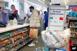 FILE - A customer makes a purchase at a drug store selling at-home coronavirus COVID-19 tests in the Morningside Heights neighborhood of Manhattan in New York City, Feb. 6, 2022.