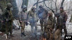 Ukrainian service members warm themselves around a fire in the Luhansk region, March 3, 2022.