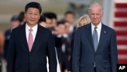 Presiden China Xi Jinping dan Joe Biden yang saat itu menjabat sebagai wakil presiden AS berjalan di karpet merah di landasan selama upacara kedatangan di Pangkalan Angkatan Udara Andrews, 24 September 2015. (Foto: AP)