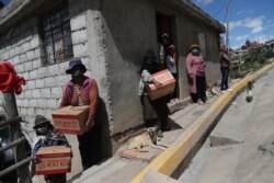 Residents wearing protective face masks hold food boxes distributed by the government during a lockdown to contain the spread of COVID-19, on the outskirts of Quito, Ecuador, May 27, 2020.
