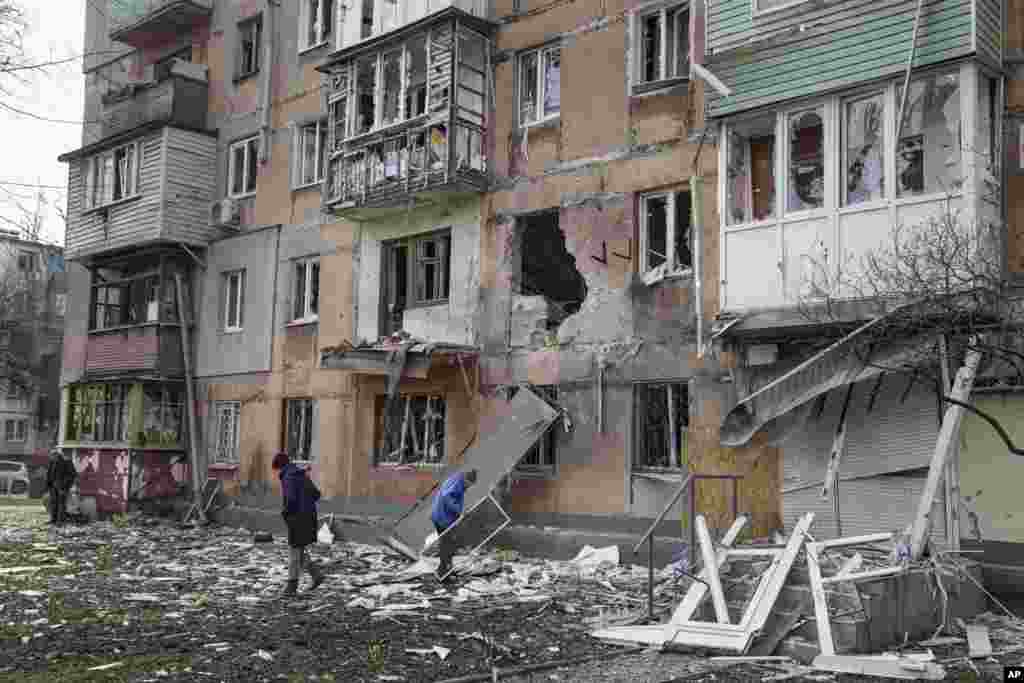 People walk outside an apartment building hit by Russian shelling in Mariupol, March 7, 2022.