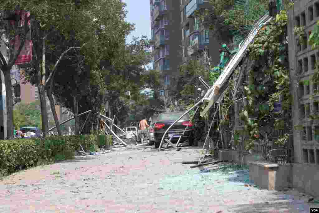 天津爆炸事故现场，核心爆炸区周围多座居民楼窗户被震碎，高速公路桥梁受损，多辆大货车被炸翻，小汽车起火或被砸，多名当地居民仍逗留在事故现场。（美国之音记者东方拍摄）