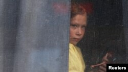 A girl looks out a bus window as civilians evacuating from the Russian-controlled Kherson region of Ukraine arrive at a rail station after Russian-installed officials ordered the evacuation of the area along the eastern bank of the Dnipro River in Dzhankoi, Crimea,Nov. 2, 2022.
