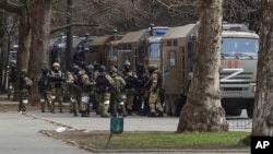 FILE - Russian army soldiers stand next to their trucks during a rally against Russia's occupation, in Svoboda (Freedom) Square in Kherson, Ukraine, March 7, 2022. Russia’s military announced Nov. 9, 2022, that it’s withdrawing from Kherson and nearby areas.