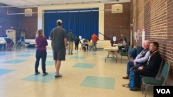 International election observers John Ault and Harry Busz of the UK-based Democracy Volunteers watch the voting process inside a polling station in Alexandria, Virginia. (Steve Herman/VOA)