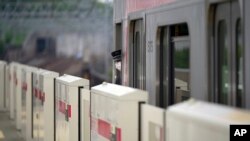 Seorang kondektur perempuan di kereta api Stasiun Tamagawa Tokyu Railways, Rabu, 20 April 2022 . (AP Photo/Eugene Hoshiko)