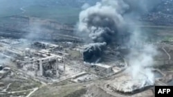 This handout video grab taken from a footage released by Mariupol City Council on Apr. 19, 2022 shows clouds of smoke billowing above Azovstal steel plant and the destroyed gates of Azov Shipyard. (Photo by Handout / Mariupol City Council / AFP)