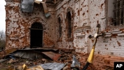 FILE - A metal cross that used to be on the top of the dome stands outside of the damaged church in Lukashivka, in northern Ukraine, Apr. 22, 2022.