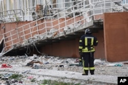 A firefighter stands next to an apartment building damaged by Russian shelling in Odesa, Ukraine, April 23, 2022.