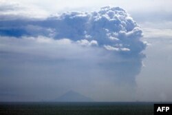 Gunung Anak Krakatau menyemburkan asap tebal ke udara, diambil dari pantai Pasauran, Anyer, Serang, 24 April 2022.(DZIKI OKTOMAULIYADI / AFP)