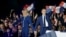 French President and La Republique en Marche (LREM) party candidate for re-election Emmanuel Macron (R) holds his fist in the air as he holds Brigitte Macron's hand after his victory in France's presidential election, at the Champ de Mars in Paris, April 24, 2022.
