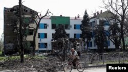 A man rides a bicycle near a building heavily damaged during Ukraine-Russia conflict in the southern port city of Mariupol, Ukraine April 25, 2022.