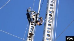 FILE- Workers for the country's electricity supplier ESCOM work on electricity poles damaged by Tropical Storm Ana, in Chikwawa district, Malawi. (Lameck Masina/VOA)