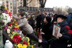People place flowers to pay their respect at a memorial dedicated to people who died in early 2014 in clashes with security forces in central Kyiv during mass protests that ousted pro-Russia president Viktor Yanukovych, at Independence Square (Maidan) in Kyiv, Ukraine, Feb. 20, 2019.