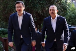 Menteri Luar Negeri Ukraina Dmytro Kuleba, kiri, disambut oleh Menlu Turki Mevlut Cavusoglu menjelang pertemuan tripartit mereka dengan Menteri Luar Negeri Rusia Sergey Lavrov, di Antalya, Turki, Kamis, 10 Maret 2022. (Foto: via AP)