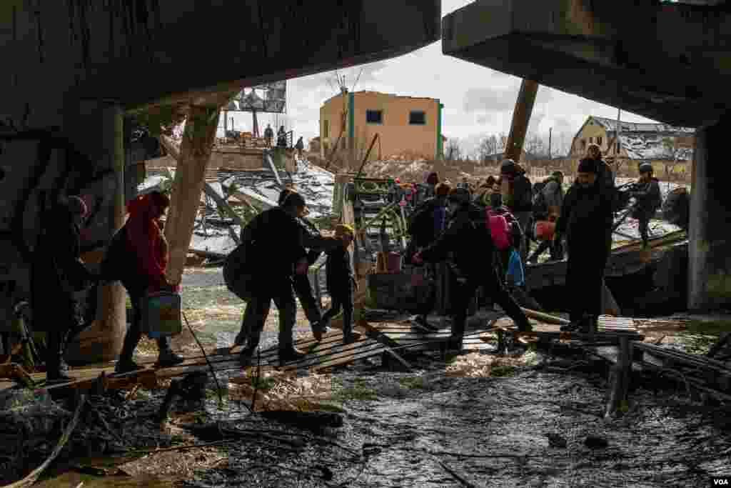 Women, children and the elderly had to go through the Irpin River after the bridge that links Kyiv to this small town was bombed by Ukrainian forces as a strategy to slow down the Russian troops&#39; advance, in Irpin, Ukraine, March 8, 2022. (Yan Boechat/VOA