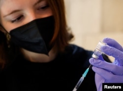 Seorang sukarelawan menyiapkan jarum suntik berisi dosis Comirnaty, vaksin COVID-19 Pfizer-BioNTech, di pusat vaksinasi di Katedral St. Stephen, di Wina, Austria, 5 Februari 2022. (REUTERS/Leonhard Foeger)