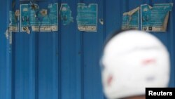 រូបឯកសារ៖ បុរសម្នាក់ឈរមុខរបងដែលមានបិទស្លាកសម្គាល់គណបក្សសង្គ្រោះជាតិ ដែលគណបក្ស​នេះ​ត្រូវបានតុលាការកំពូលរំលាយ នៅជាយរាជធានីភ្នំពេញ ថ្ងៃទី ២០ ខែវិច្ឆិកា ឆ្នាំ ២០១៧។