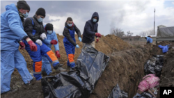 Polaganje tela ubijenih u masovnu grobnicu u Marijupolju, 9. mart 2022.
