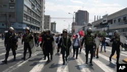 Flanked by police trying to keep order, supporters of ousted President Pedro Castillo march while demanding his return to power, Dec. 9, 2022.