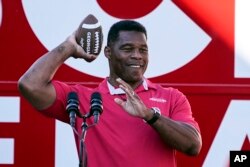 ARHIVA -Republikanski kandidat za Senat Heršel Voker baca loptu pristalici na predizbornom mitingu 29. novembra 2022. u Griznborou u Džordžiji.