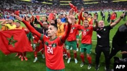 Para pemain Maroko melakukan selebrasi bersama pendukung setelah memenangkan pertandingan sepak bola perempat final Piala Dunia Qatar 2022 antara Maroko dan Portugal di Stadion Al-Thumama di Doha pada 10 Desember 2022. (Foto: AFP/Kirill Kudryavtsev)