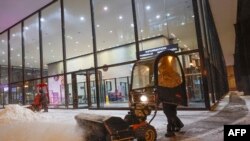 A person uses a snow blower to clear a sidewalk outside of Union Station in Chicago, Dec. 22, 2022, during a winter storm ahead of the Christmas holiday.