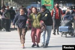 A family member of a victim of the aircraft that crashed in Pokhara is escorted as she mourns at the airport in Kathmandu, Nepal, Jan. 15, 2023.