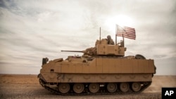 FILE - American soldiers drive a Bradley Fighting Vehicle during a joint exercise with Syrian Democratic Forces at the countryside of Deir Ezzor in northeastern Syria, Dec. 8, 2021.