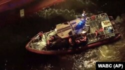 Rescued sailors are seen on board a smaller boat after leaving the Silver Muna tanker ship, Dec. 14, 2022 in New York.