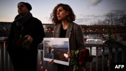 A woman holds a photographic portrait during tribute to Mohammad Moradi, an Iranian man who killed himself after jumping into the Rhone river to raise awareness about the situation of the Iranian people, in Lyon on Dec. 27, 2022.