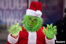 Seseorang mengenakan kostum Grinch di Times Square, New York City, AS, 9 Desember 2022. REUTERS/David 'Dee' Delgado
