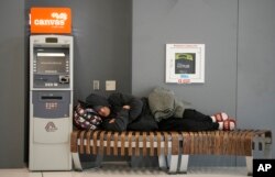 A traveler sleeps on a bench near the Southwest Airlines check-in counter at Denver International Airport, Dec. 27, 2022.