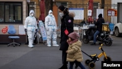 身穿防护服的大白站在北京一居民小区的大门处执勤。（2022年12月7日）