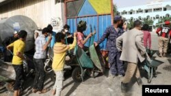 FILE - Workers wait to ferry foodstuff outside an aid distribution center in Sana'a, Yemen, Sept. 28, 2022.