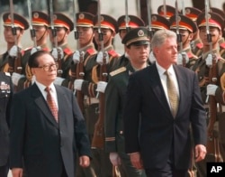 FILE - Then U.S. President Bill Clinton, right, and the then Chinese President Jiang Zemin, left, review Chinese troops during arrival ceremonies at east the plaza of the Great Hall of the People in Beijing, June 27, 1998.