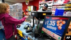 FILE - A Mega Millions sign displays the estimated jackpot of $1.35 billion as a customer purchases a Mega Millions ticket at the Cranberry Super Mini Mart in Cranberry, Pa., Jan. 12, 2023.