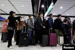 Para pelancong mengantri di pos pemeriksaan perbatasan Lok Ma Chau Hong Kong pada hari pertama China membuka kembali perbatasan di tengah pandemi COVID-19 di Hong Kong, China, 8 Januari 2023. (Foto: REUTERS/Tyrone Siu)