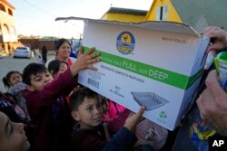 FILE - Migrant children hold a box filled with food and clothes outside a shelter in Tijuana, Mexico, Dec. 21, 2022.