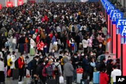 In this photo released by Xinhua News Agency, people with their luggage prepare to catch their trains at the North Railway Station in Shenzhen in south China's Guangdong province, Jan. 7, 2023.