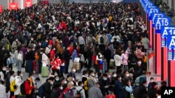 In this photo released by Xinhua News Agency, people with their luggage prepare to catch their trains at the North Railway Station in Shenzhen in south China's Guangdong province, Jan. 7, 2023. 