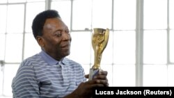 Le légendaire footballeur brésilien Pelé pose pour un portrait avec son trophée de la Coupe du monde 1958 lors d'une interview à New York, États-Unis, le 26 avril 2016.