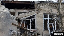A woman measures size of a broken hospital window following recent shelling in the course of Russia-Ukraine conflict in Donetsk, Russian-controlled Ukraine, Dec. 15, 2022.