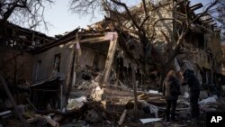 Serhii Kaharlytskyi, right, stands outside his home, destroyed after a Russian attack in Kyiv, Jan. 2, 2023. Kaharlytskyi's wife Iryna died in the attack on Dec. 31, 2022.