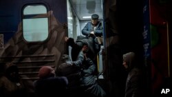 Ukrainians board a train at the Kherson railway station, Nov. 21, 2022. Ukrainian authorities are evacuating civilians from recently liberated sections of the region, fearing a lack of heat, power and water due to Russian shelling will make conditions unlivable this winter.