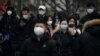 Commuters wearing face masks walk along a street in the central business district in Beijing, Jan. 12, 2023. 