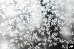 Frost forms on a storm window during a blizzard warning, Dec. 23, 2022, in Iowa City, Iowa.