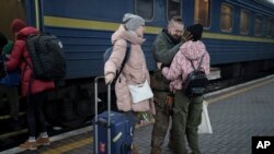 Ukrainian soldier Vasyl Khomko, 42, meets his daughter Yana and his wife Galyna, left, at the train station in Kyiv, Dec. 31, 2022. 