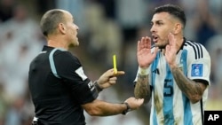 Referee Antonio Mateu shows a yellow card to Argentina's Leandro Paredes during the World Cup match in Lusail, Qatar, Dec. 9, 2022.