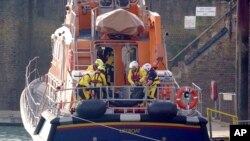Members of the Dover lifeboat place a body bag on a stretcher after a large search and rescue operation launched in the Channel off the coast of Dungeness, in Kent, Britain, Dec. 14, 2022, following a small boat capsized in the freezing water.